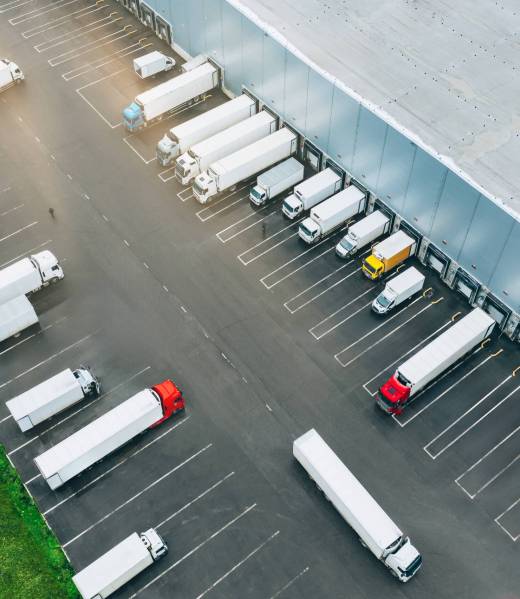 Aerial view of many trucks at the loading docks of a large distribution warehouse.